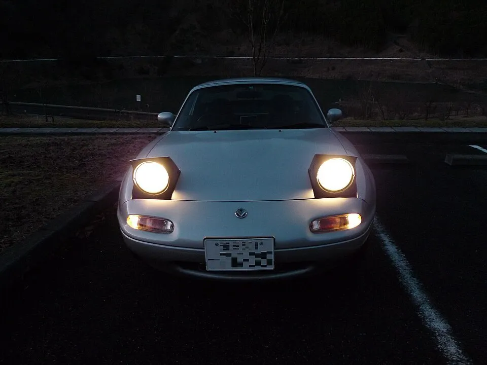 Retro white sports car (Mazda MX-5) with flip lights up and shining