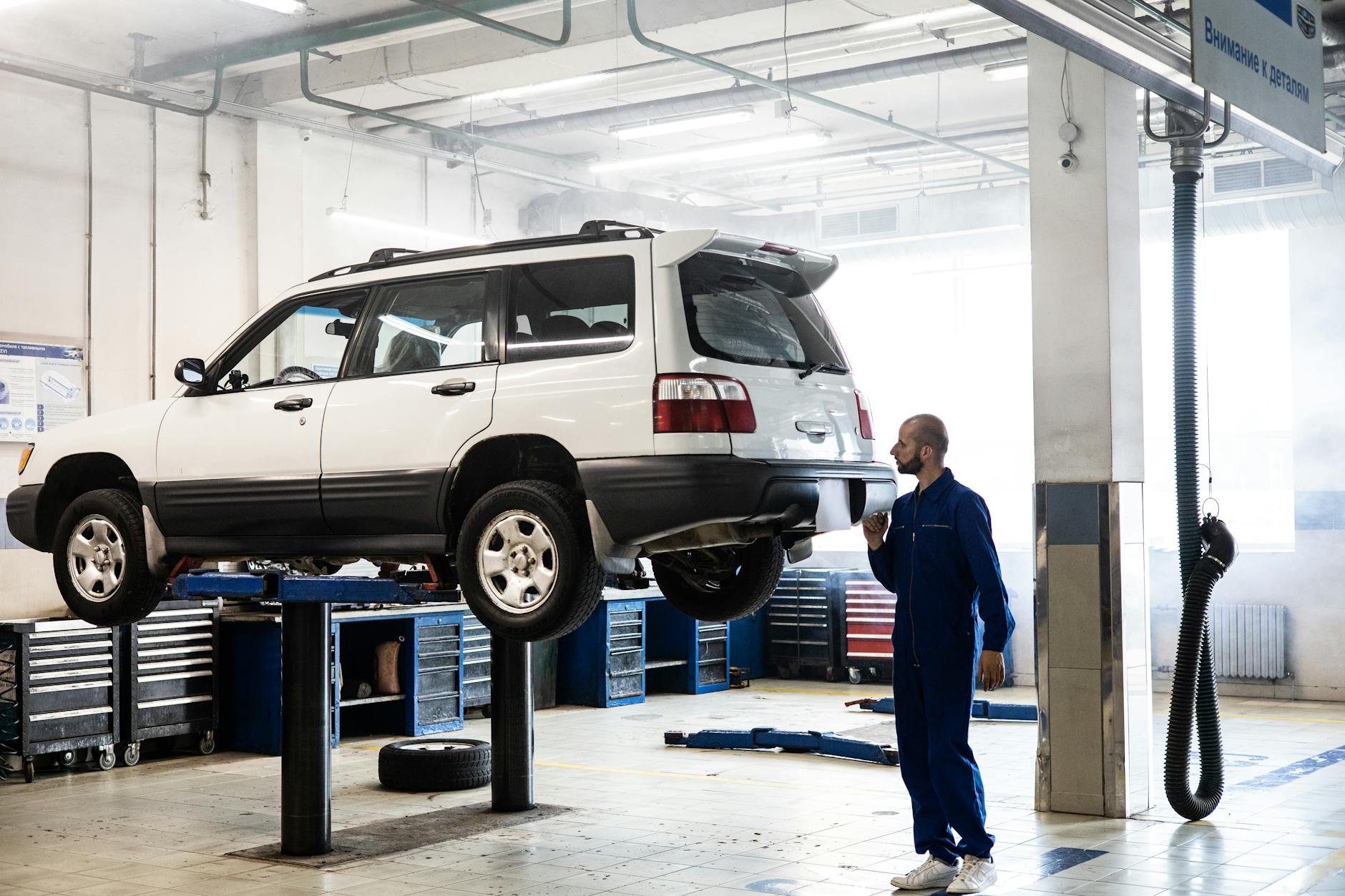 man in blue coverall inspecting a white car